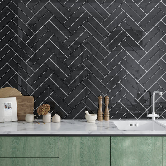 Black 3x12 glossy glass subway tile arranged in herringbone pattern with white grout lines