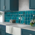 glossy teal green ceramic square tiles with 0.5x8 pencil tile trim on kitchen backsplash