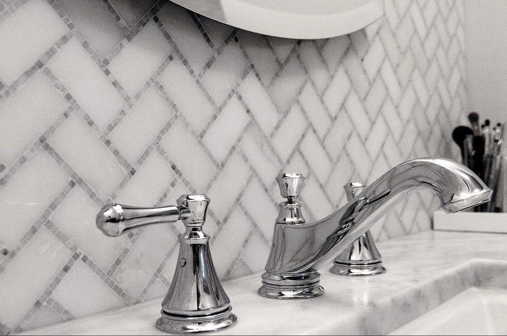 white and gray polished marble tiles arranged in herringbone mosaic pattern