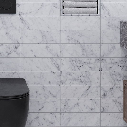 White polished Bianco Carrara marble subway tile 4x12 installed on bathroom wall