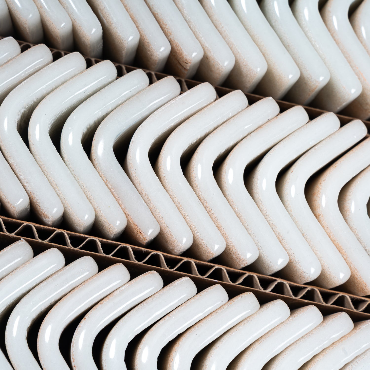 matte clay beige 2x2 recycled glass corner tiles stacked in corrugated cardboard