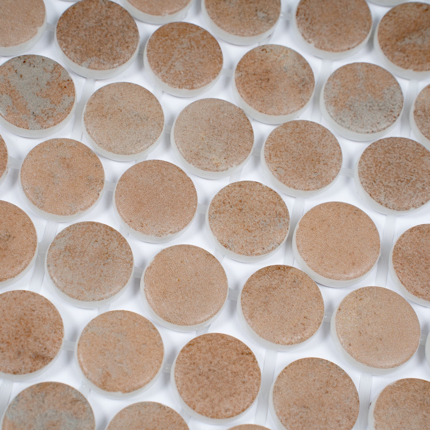 clay beige matte recycled glass round mosaic tiles arranged in a grid pattern