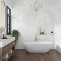 Large-format frosted white 24x48 polished porcelain tile on bathroom walls with a freestanding tub and warm wood flooring