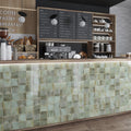Glossy sage green 4x4 ceramic square tiles on bar front wall in kitchen or café setting