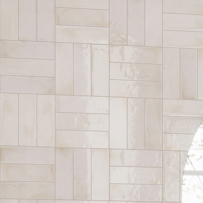 glossy white ceramic subway tile wall with varied 3x8 tile patterns and reflective finish