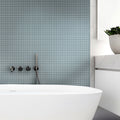 Stone blue glossy square glass mosaic tiles on bathroom wall behind bathtub