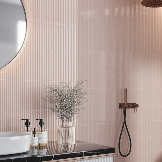 Glossy pink 2x8 ceramic subway tile arranged vertically on bathroom wall with fluted texture