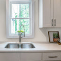 Glossy white recycled glass penny round mosaic tile backsplash in the kitchen around the window
