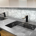 Polished white marble penny round mosaic tile backsplash with mixed circle sizes in bathroom setting